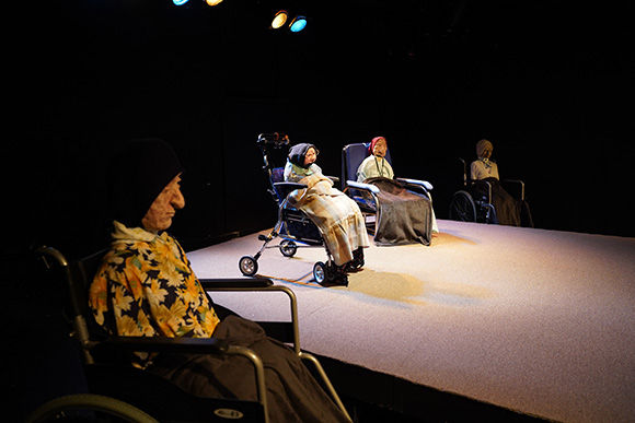 할머니의 모습을 한 네 개의 인형이 각각 휠체어에 앉아 있다. 휠체어는 일렬로 객석을 마주 보게 놓여 있다. 