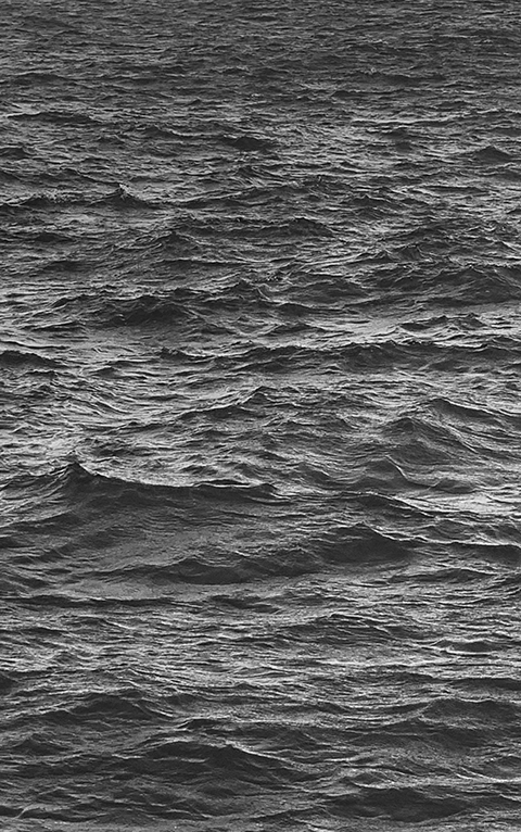 세로로 긴 흑백의 이미지. 다른 것은 아무것도 없는, 파도가 치고 있는 바다의 한가운데다.