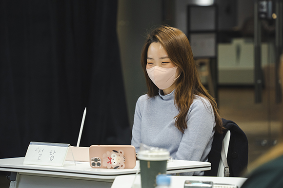 작가 박예지. 밝은 갈색의 머리의 끝부분에 약간의 웨이브가 있다. 옅은 하늘색의 니트와 분홍색 마스크를 쓰고 웃고 있다. 책상 위의 이름표에는 ‘설탕’이라고 쓰여있다.