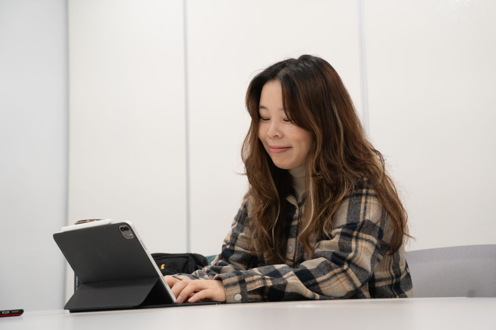 배우 성수연. 슬며시 미소를 머금고 태블릿 PC에 연결된 키보드에 손을 얹고 있다.