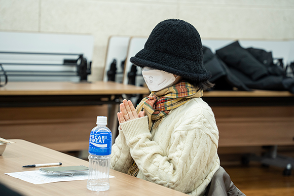 리뷰 필진 진송. 검은 벙거지 모자에 하얀 마스크를 쓰고 있다. 아이보리색 니트에 베이지색과 붉은색, 녹색의 체크무늬 목도리를 둘렀다.