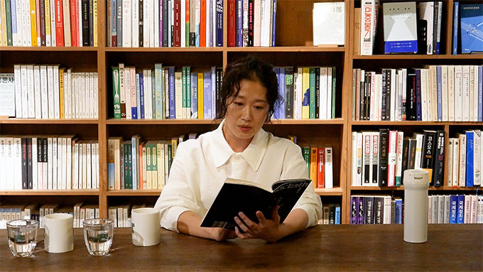 <맥베스 1인 낭독극>의 공연 사진. 흰 블라우스를 입은 배우 곽지숙이 기다란 나무 책상에 앉아 『맥베스』 책을 읽고 있다. 오른손으로 책등을 받치고, 왼손으로는 책장을 지지하였다.
그는 파마한 머리를 뒤로 묶었다. 코 높이까지 흘러내린 구불구불한 옆머리가 보인다.
배우를 기준으로 책상 왼편으로 물이 담긴 투명한 잔 두 개와 불투명한 흰색 잔 두 개가 줄지어 놓여 있고, 오른편으로 흰색 텀블러 하나가 놓여 있다.
배우의 뒤편으로 책들이 가득 꽂힌 나무 책장이 보인다.