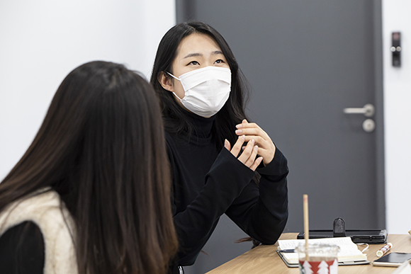 가 채윤. 검은색 목폴라의 소매가 손등을 덮는다. 허공을 보며 무언가 생각하는 듯한 표정을 짓고 있다. 